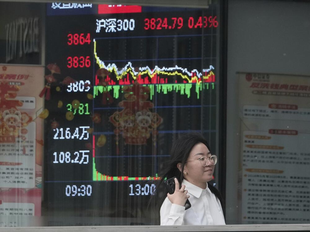 A woman passes by a stock index at a brokerage in Beijing, Wednesday.