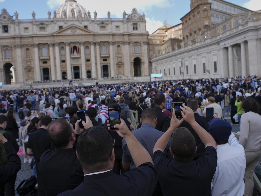 Faithful take photos as black smoke billows from the Sistine Chapel during the conclave to elect a new pope at the Vatican on Thursday.