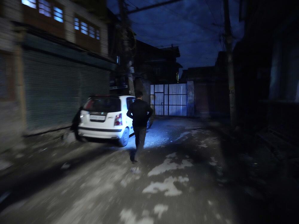 A Kashmiri man using a cellphone light during a blackout is seen after residents of the city of Jammu reported hearing explosions and sirens in Srinagar, Indian-controlled Kashmir, Thursday.