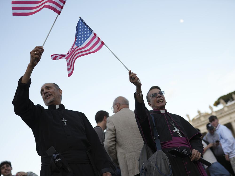Clerics wave US flags during the speech of the newly elected Pope Leo XIV at the Vatican, Thursday, May 8.