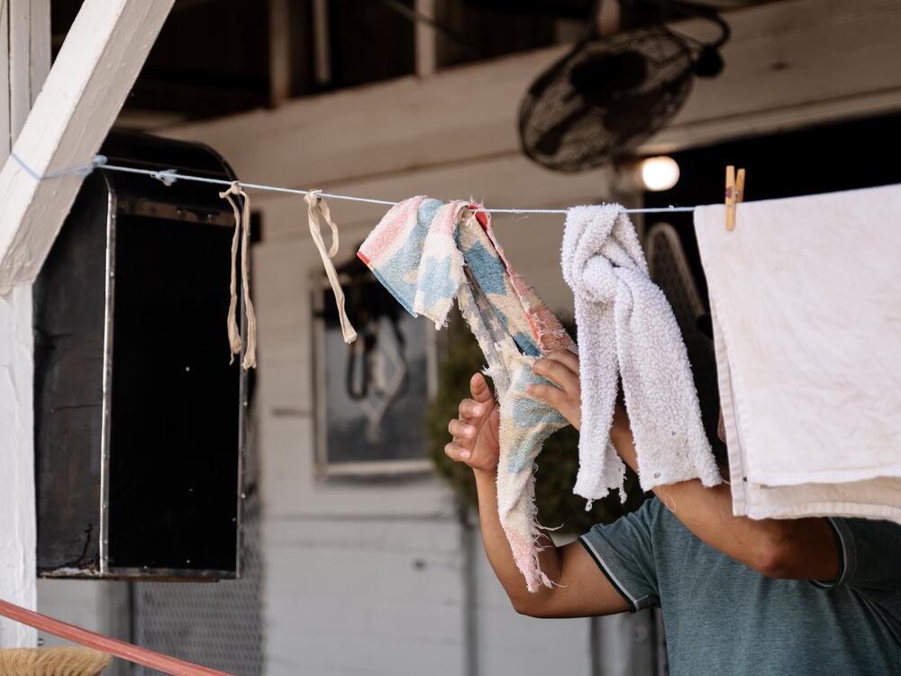 A worker hangs rags used for cleaning on a clothesline outside of horse racing stables in Louisville, Ky., on April 29, 2025. Workers on the backside of the track are responsible for general upkeep of the stables and bathing the race horses.