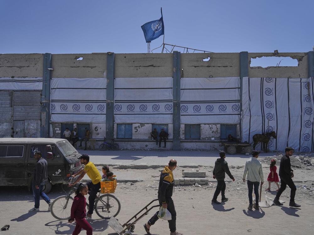 Palestinians walk next to the closed humanitarian aid distribution center of UNRWA, the U.N. agency helping Palestinian refugees in Jabaliya, Gaza Strip on Tuesday, April 29, 2025.