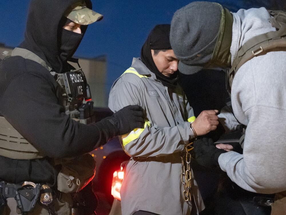 U.S. Immigration and Customs Enforcement officers use a chain to more comfortably restrain a detained person using handcuffs positioned in front.