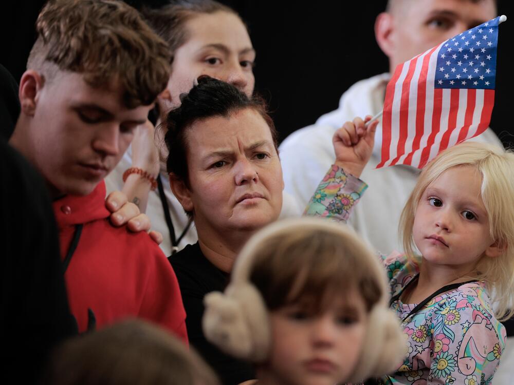 Newly arrived South Africans listen to representatives from Homeland Security and the State Department deliver welcome statements in a hangar at Atlantic Aviation Dulles near Washington Dulles International Airport on May 12, 2025 in Dulles, Va.