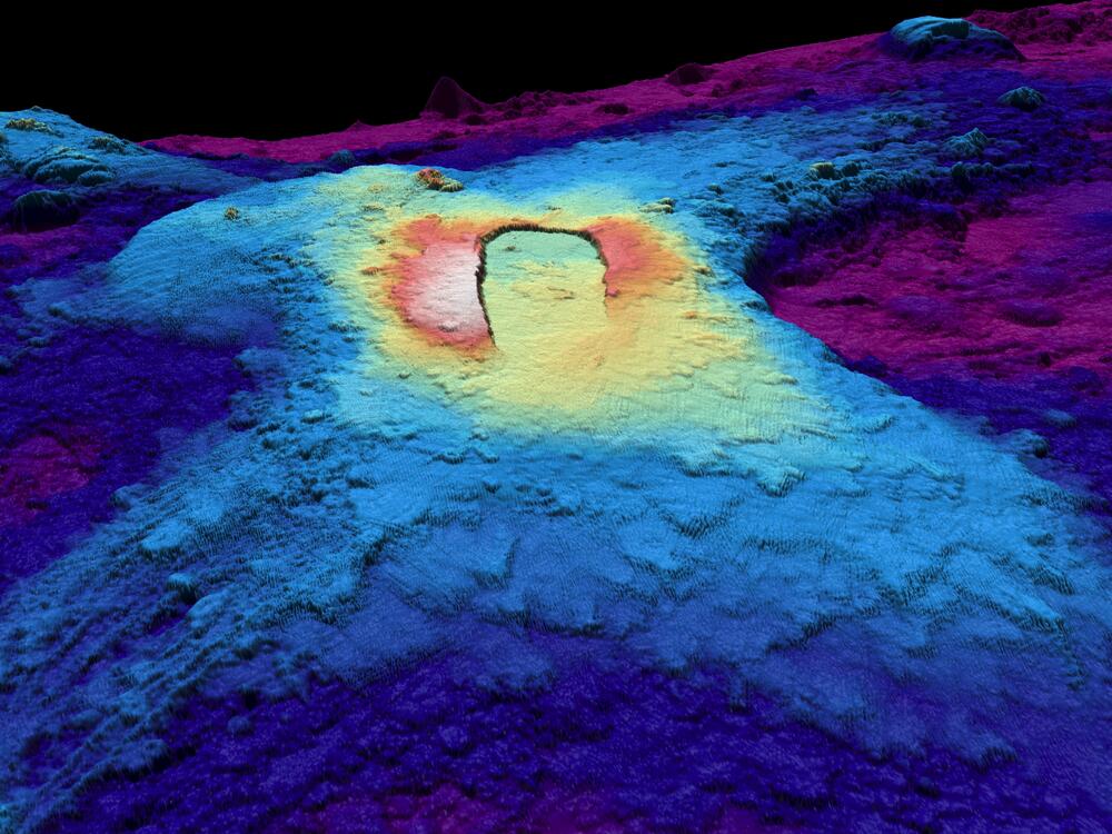 A three-dimensional map of the seabed shows the shape of the caldera of the Axial Seamount volcano. Warm colors show shallower depths and cool colors are deeper.