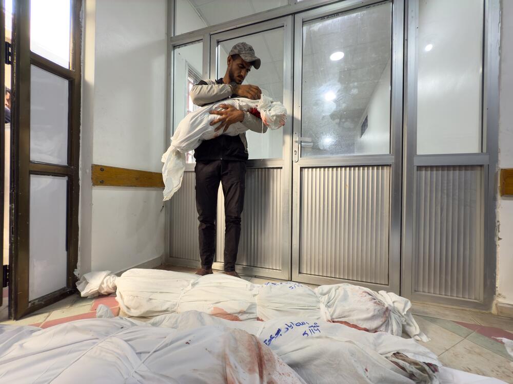 A man holds a small child's corpse wrapped in shroud, with other wrapped bodies lying on the floor, in the Indonesian Hospital in Jabalia, in northern Gaza Strip, Wednesday.