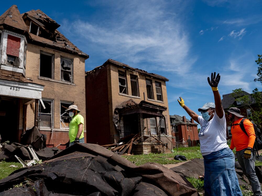 Debra El (right) rejoices after volunteers are able to get roof lining off of the road in north St. Louis on Saturday.