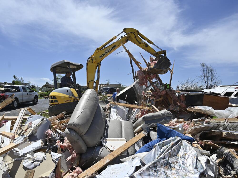 A man uses a back hoe to move debris into a pile following severe storms in London, Ky., on Saturday.