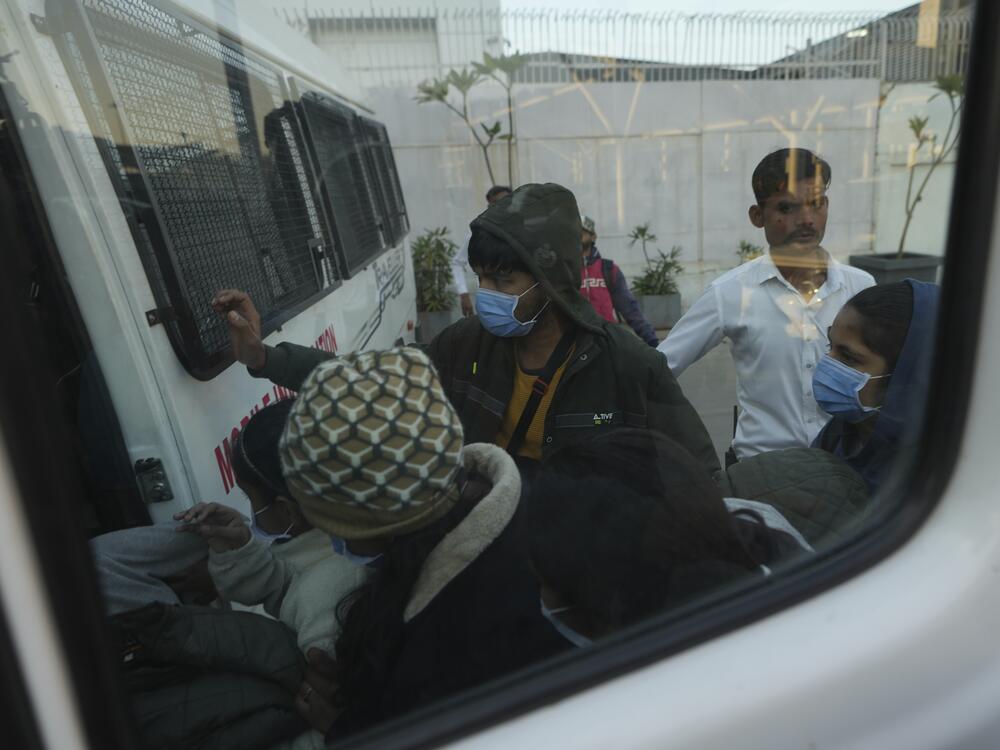 Immigrants, wearing masks, who were among those deported from the United States who arrived in a U.S. military plane in Amritsar, India, enter a police vehicle at India's Ahmedabad airport, Feb. 6.