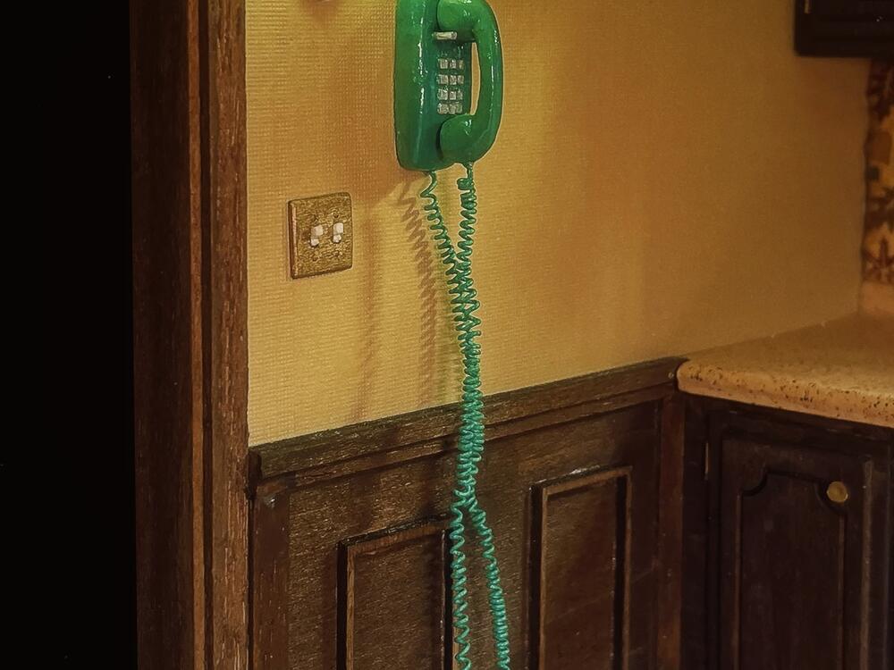 A tiny blue phone is shown in a vintage kitchen created by artist Marina Totino.