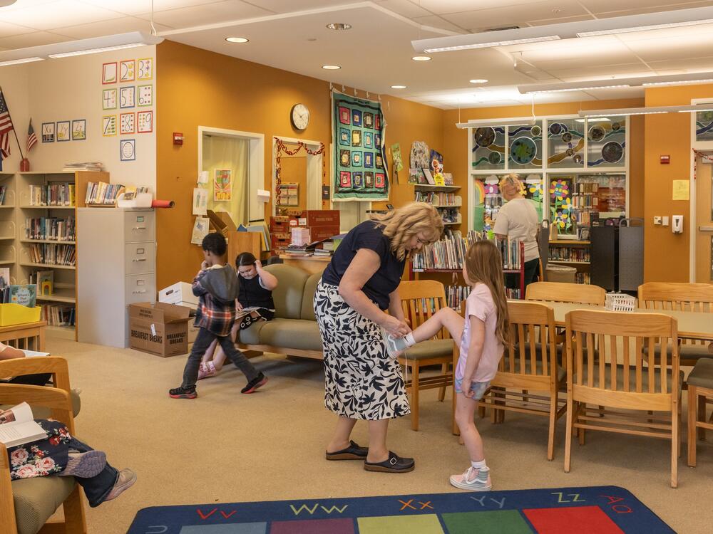 Barbara Welch has been an educator in the MSAD 54 district for nearly four decades. She helps a student tie their shoe in the library of Mill Stream.