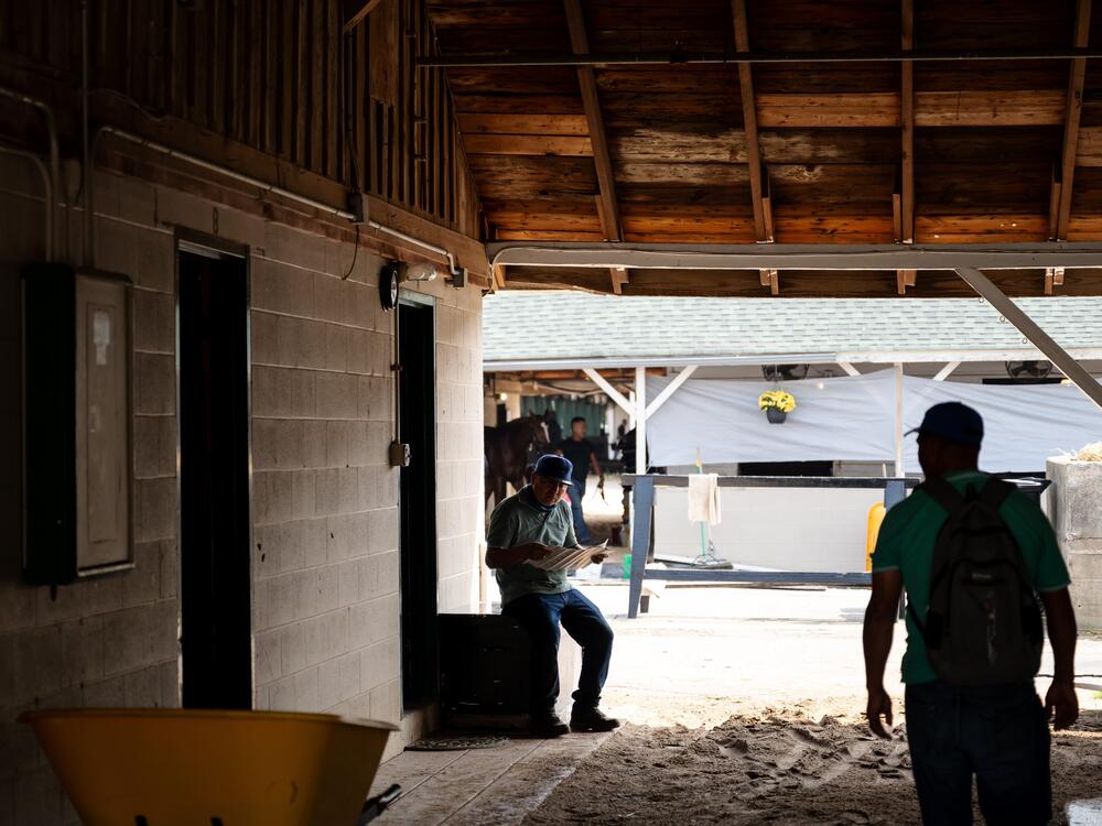 A worker reads a newspaper on the backside of a horse racing track in Louisville, Ky., on April 29.