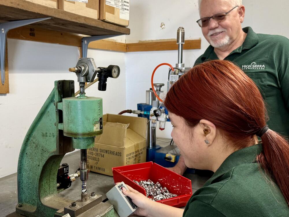 David Malcolm watches as Leslie Velasco forges showerhead nozzles. Malcolm's company makes showerheads in California using a combination of domestic and imported parts.