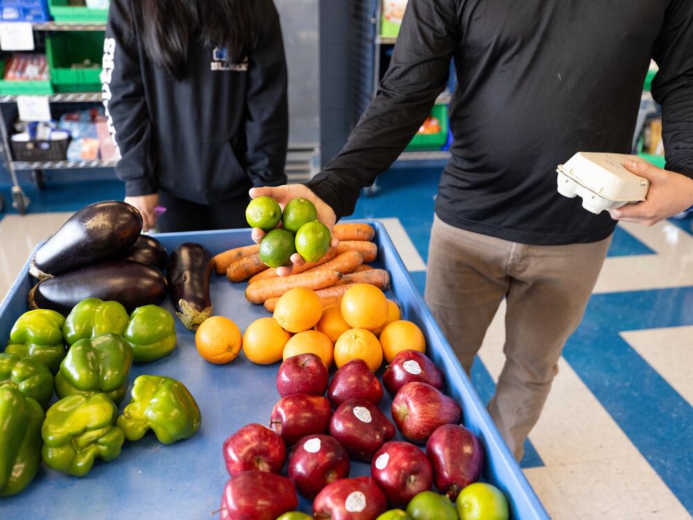 Visitors to the Island Oasis sort through the pantry's fresh produce offerings. One parent, John, said the pantry and the grocery store cards he's received from Mainzer have 