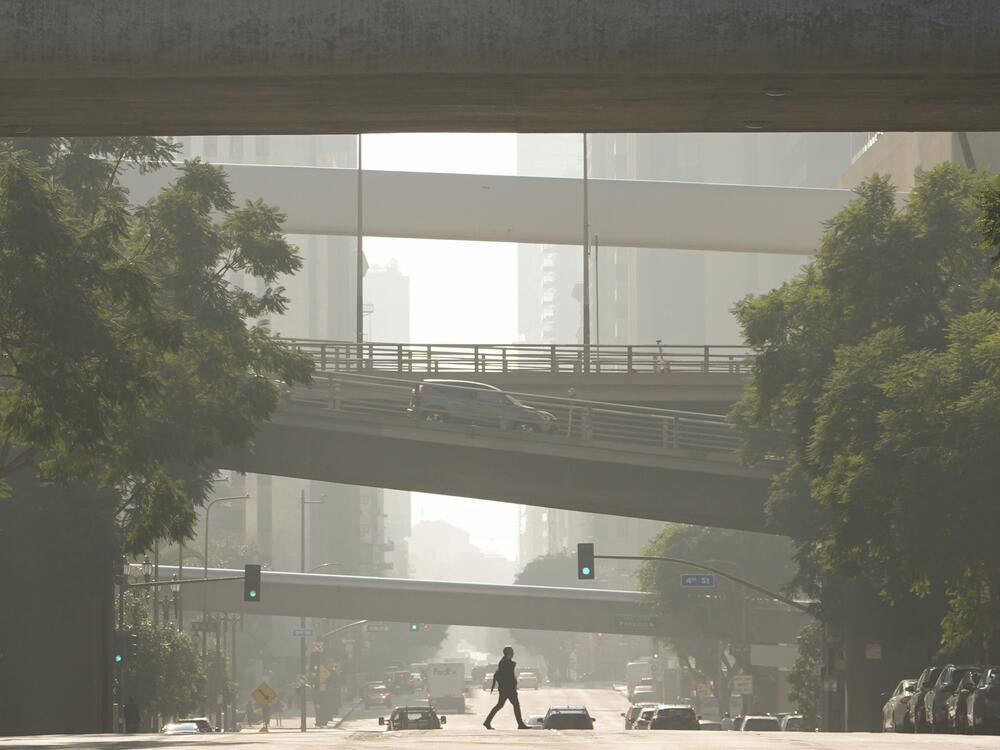 A person crosses a street as smog fills the air Wednesday, Dec. 4, 2024, in Los Angeles.