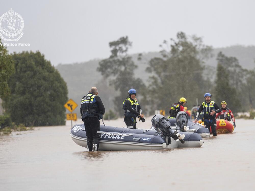 In this photo provided by the New South Wales Police, emergency workers wade through floodwaters as they prepare inflatable boats to effect rescues near Taree, Australia, Thursday, May 22, 2025.