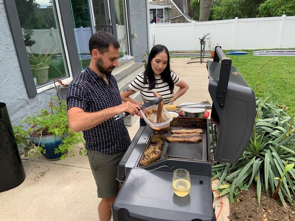 Stoio Kachev and Doanh Nghiem cook dinner on their electric grill. The couple says convenience is the main reason they switched from a propane grill — no need to refill tanks. Switching to electric also reduces their contribution to climate change.