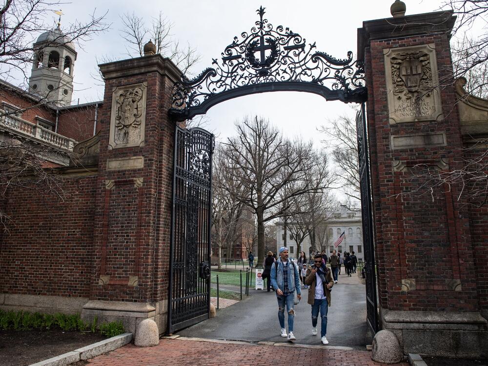 People walk through a gate as they exit Harvard Yard on the campus of Harvard University  in Cambridge, Mass.