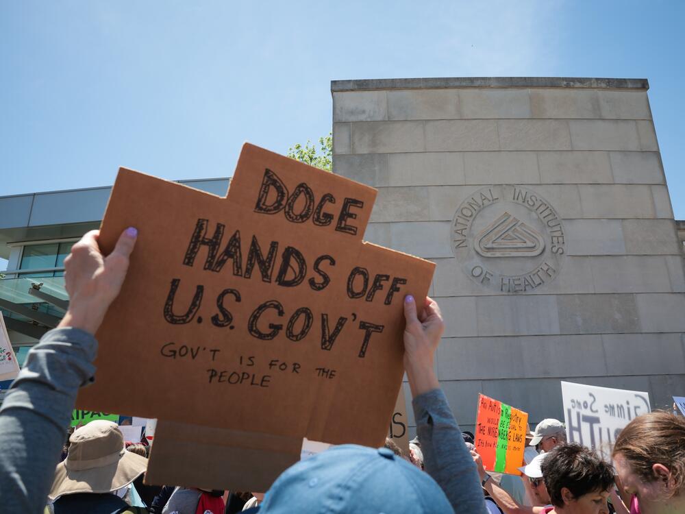 Demonstrators raise signs during a rally outside the National Institutes of Health on May 10 in Bethesda, Md.