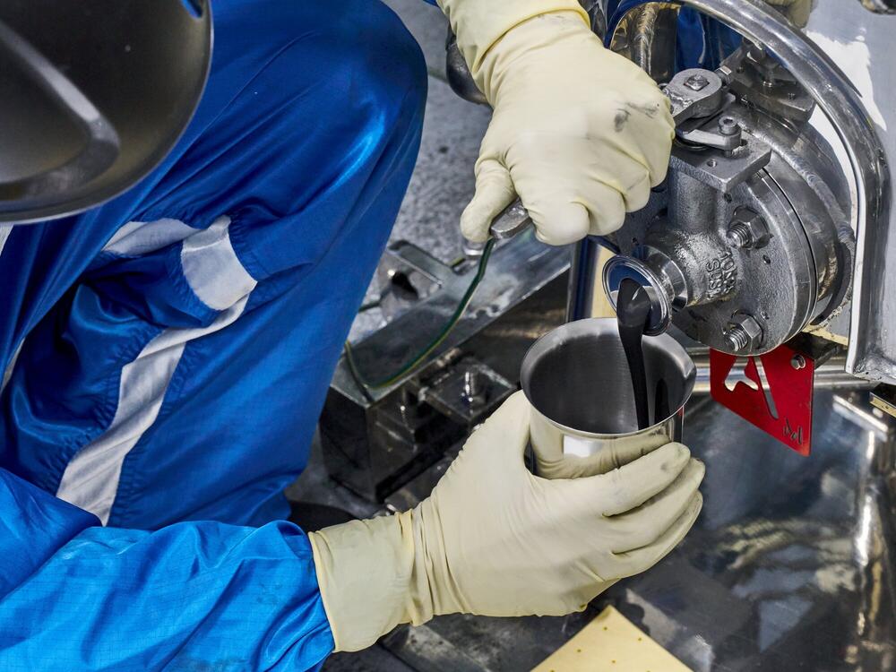 A battery technician at the General Motors Wallace Battery Cell Innovation Center takes a chemistry slurry sample.