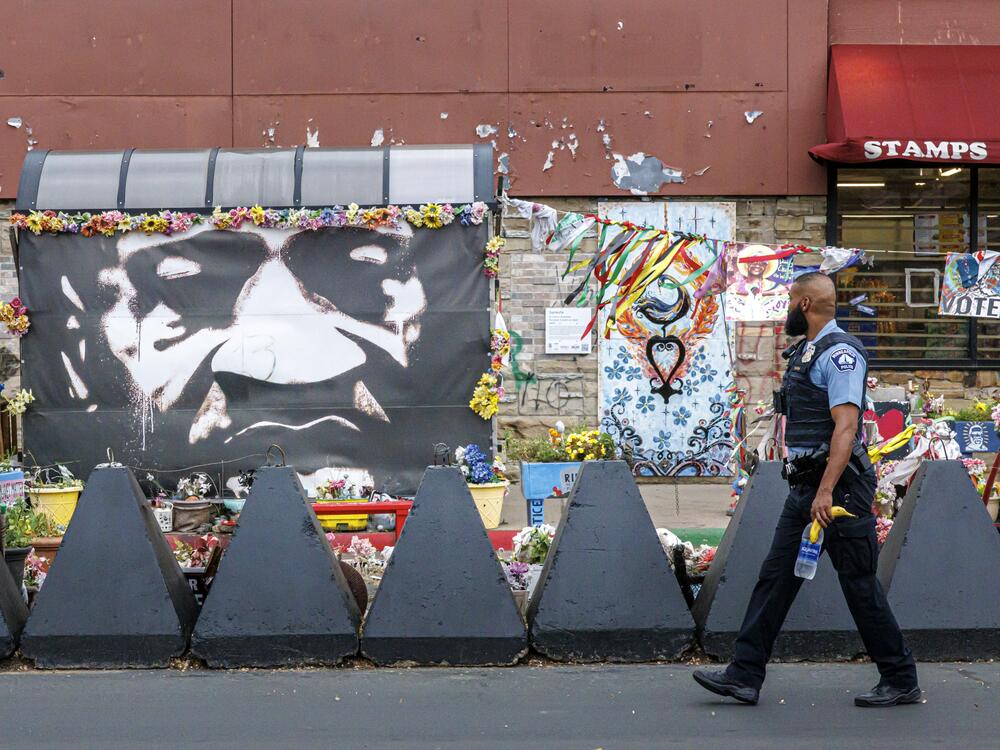 A Minneapolis police officer walks past a mural of George Floyd at the square.