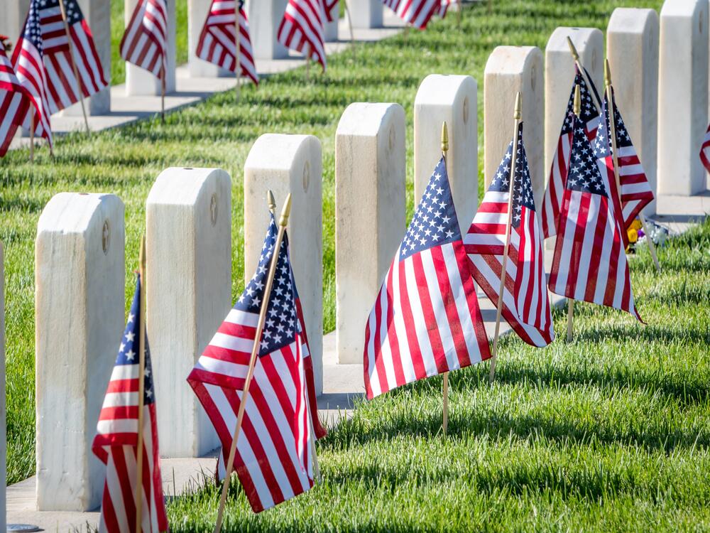 Military headstones honoring armed forces service members are decorated with American flags for Memorial Day.