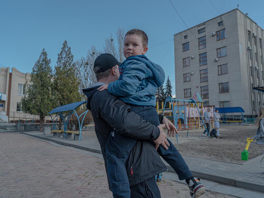 Dmytro Kluchnikov holds his son Artem in his arms at a playground in the center of Sloviansk.