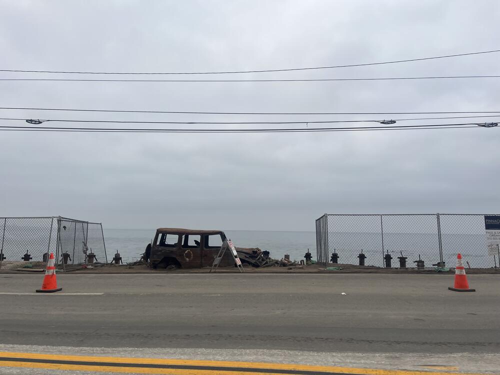 Burned-out vehicles still line the reopened section of PCH, where unobstructed views of the Pacific Ocean, previously obstructed from view, expose where multi-story homes burned to the ground.