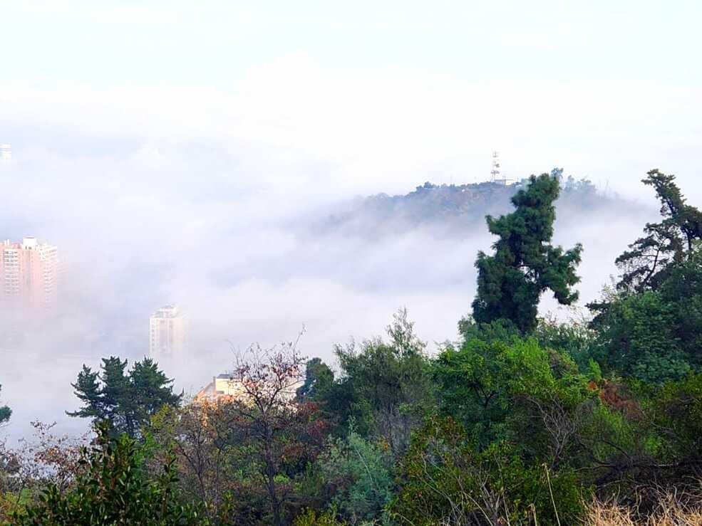 Morning fog shrouds Santiago's neighborhoods and hills during an autumn hike.