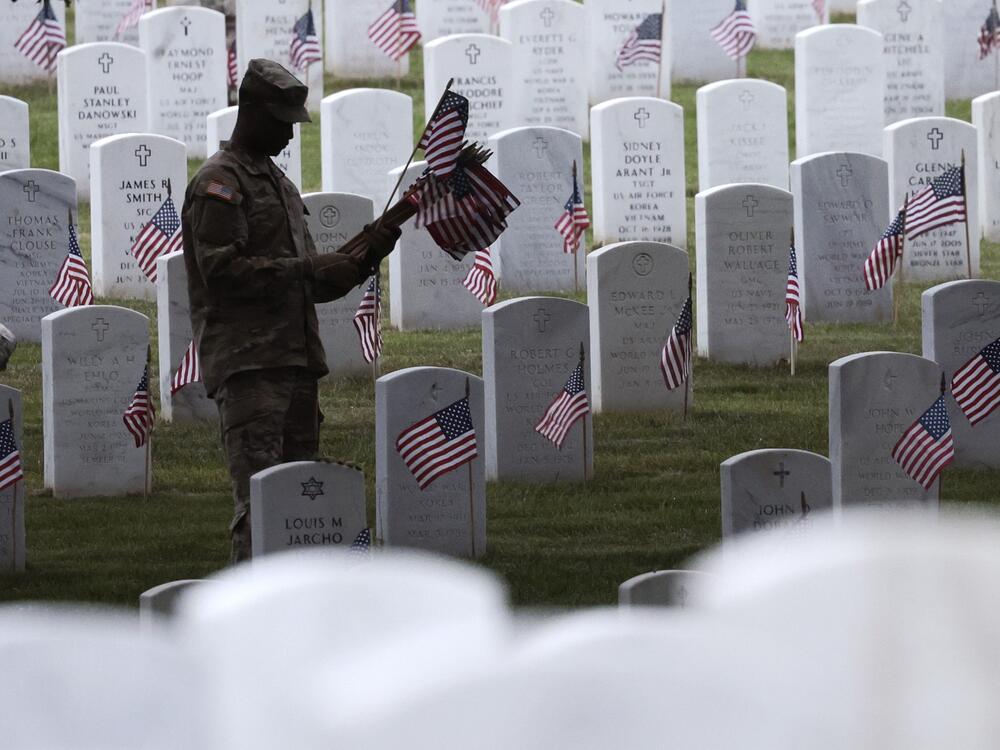 Members of the 3rd U.S. Infantry Regiment place flags at the headstones of U.S. military personnel buried at Arlington National Cemetery, in preparation for Memorial Day, on May 25, 2023, in Arlington, Va.