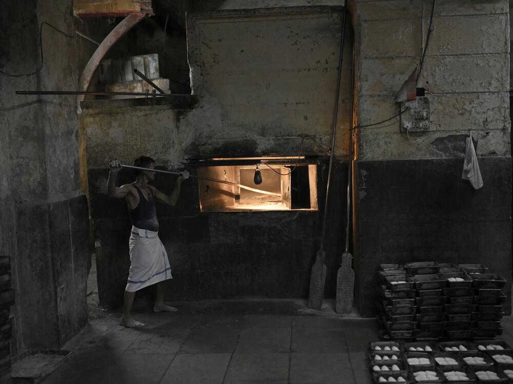 A baker places dough into a wood-fired stove at Yazdani Bakery.