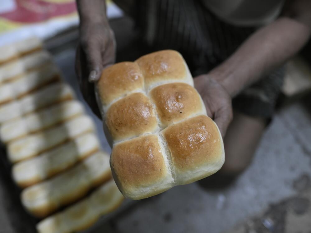 A baker holds up a loaf of pav freshly baked at the Yazdani Bakery in Mumbai. A government plan to ban wood-fired ovens in bakeries as a way to curb pollution could lead to a price increase in the beloved pav — and erase its smoky flavor.