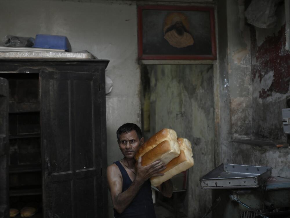 A baker carries loaves of fresh bread in the kitchen of Yazdani Bakery.