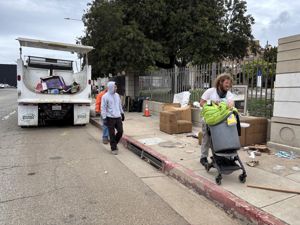 Iraq war veteran Irving Webb moves his belongings as sanitation workers clear the sidewalk, where he spent some nights in April, outside the Los Angeles VA campus.
