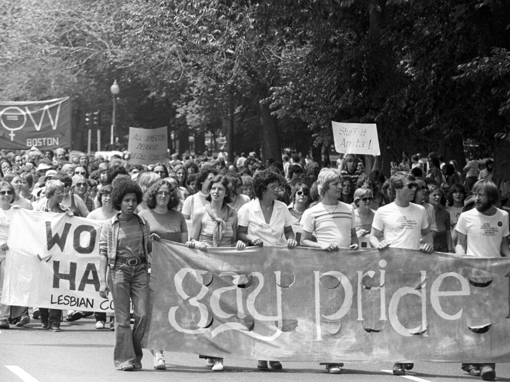 View of the large crowd, some of whom are holding up handmade signs and banners, participating in a gay and lesbian pride parade in the Back Bay neighborhood of Boston in 1975.