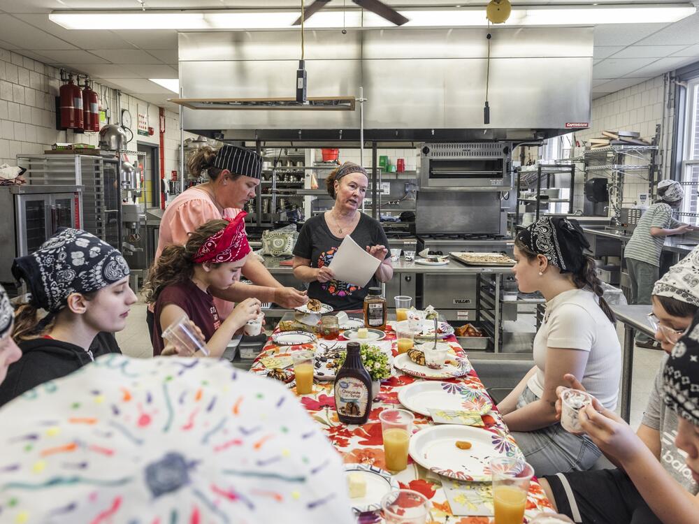 Retired chef and cooking instructor Brenda Madden gathers students around a table to enjoy their creations from the afternoon's lesson on French cuisine.