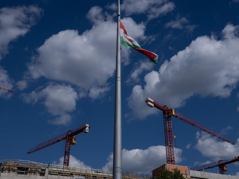 Construction cranes can be seen in Budapest's castle district, along with the Hungarian flag.