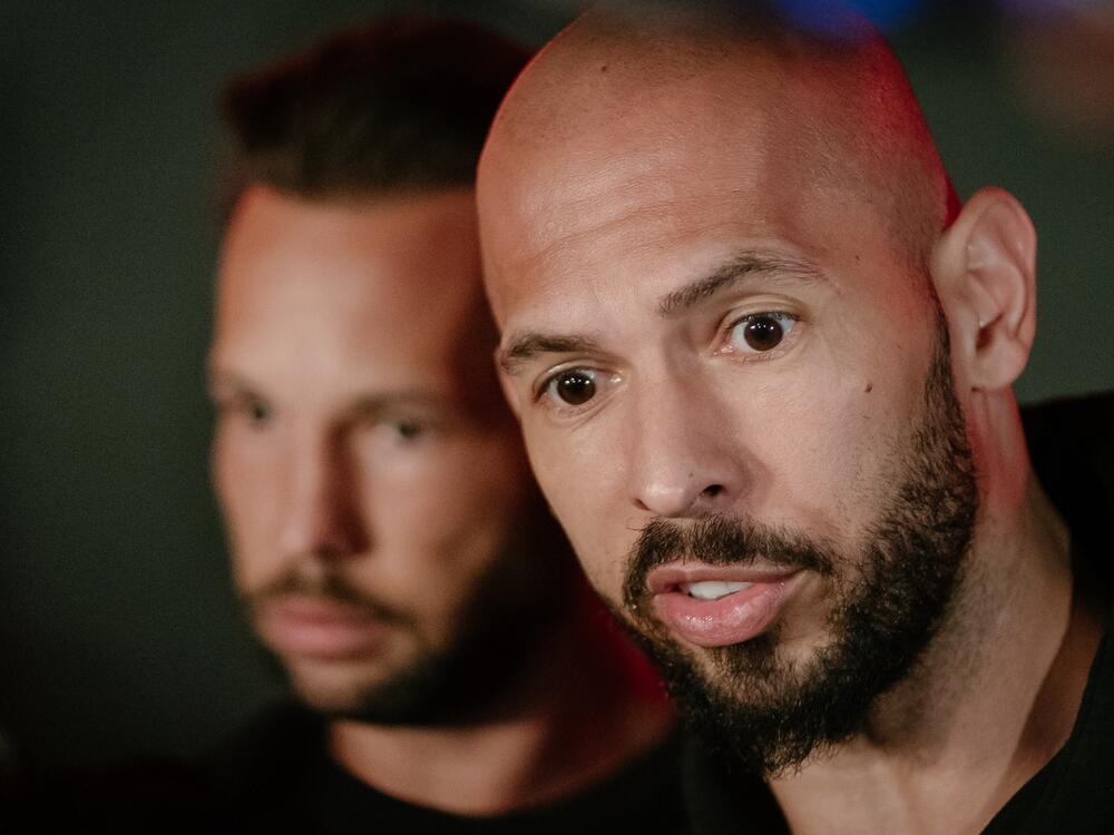 Andrew Tate and his brother Tristan Tate talk to the media outside their residence on March 23, 2025 in Bucharest, Romania.