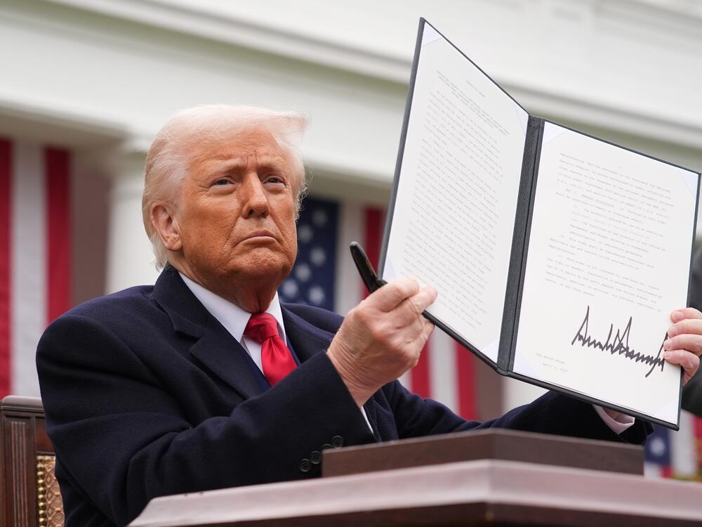 President Donald Trump displays a signed executive order imposing tariffs on imported goods during a 