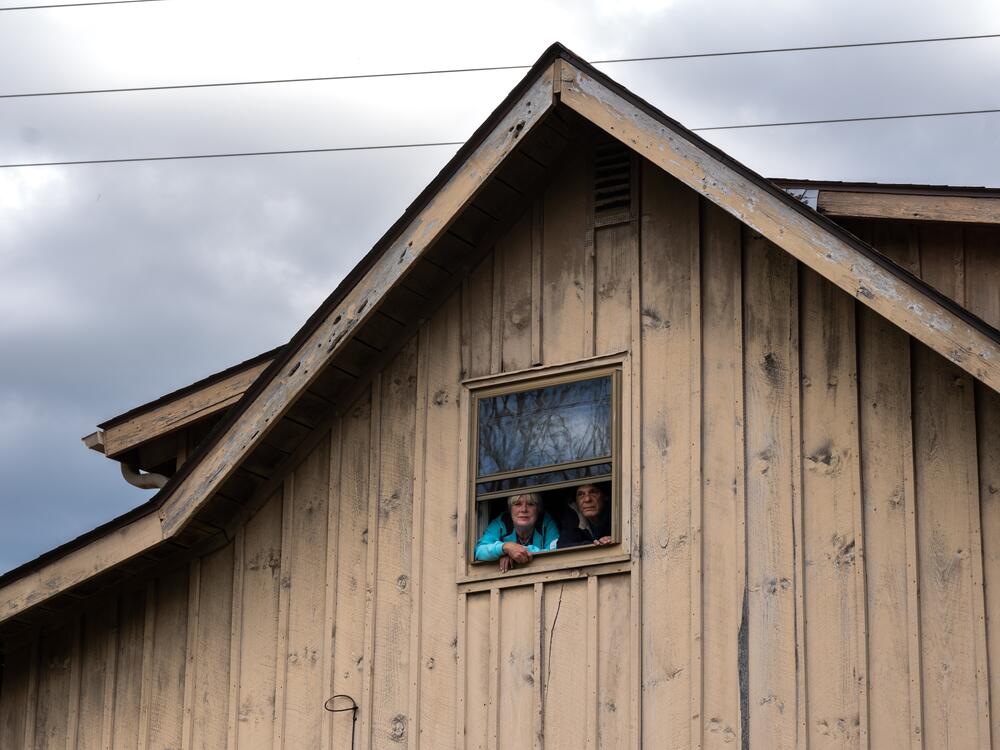 Stuart and Jackie Pacheo lean out the window where they had to watch their own home carried off by the floodwaters of Tropical Storm Helene. Mrs. Pacheo and her husband escaped the flood at her mother's home, which was right next to their own.