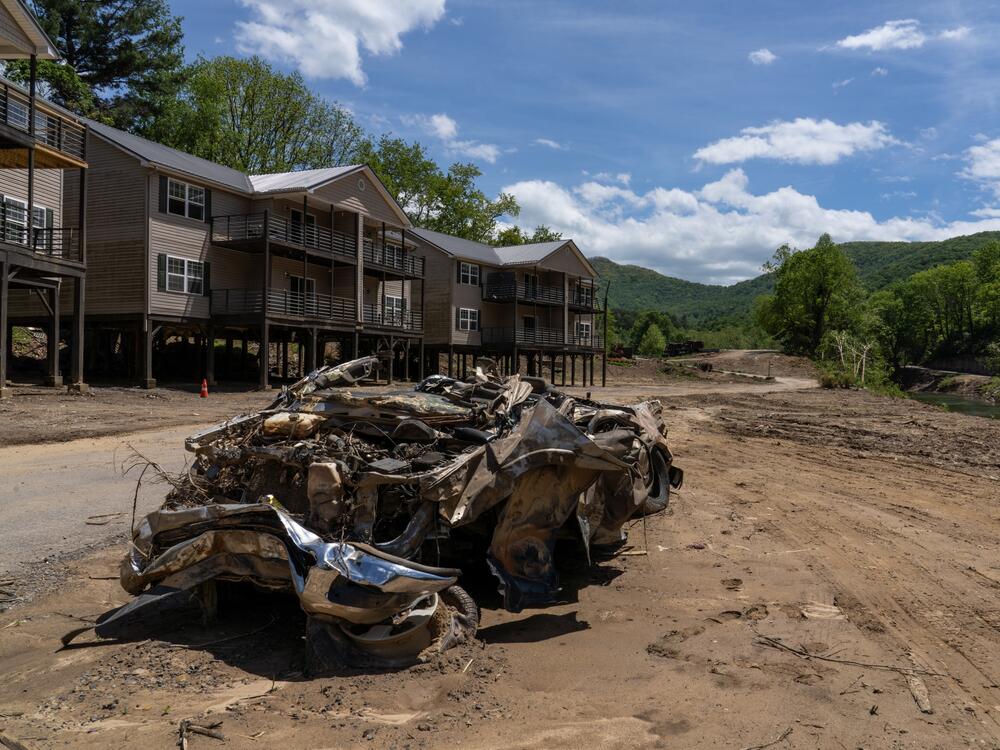 The remnants of a Dodge Ram pickup lay in front of a series of housing complexes, all damaged by the flooding following Hurricane Helene. Two of the buildings that would have blocked the view of the mountains beyond the pickup were completely washed away during the flooding.
