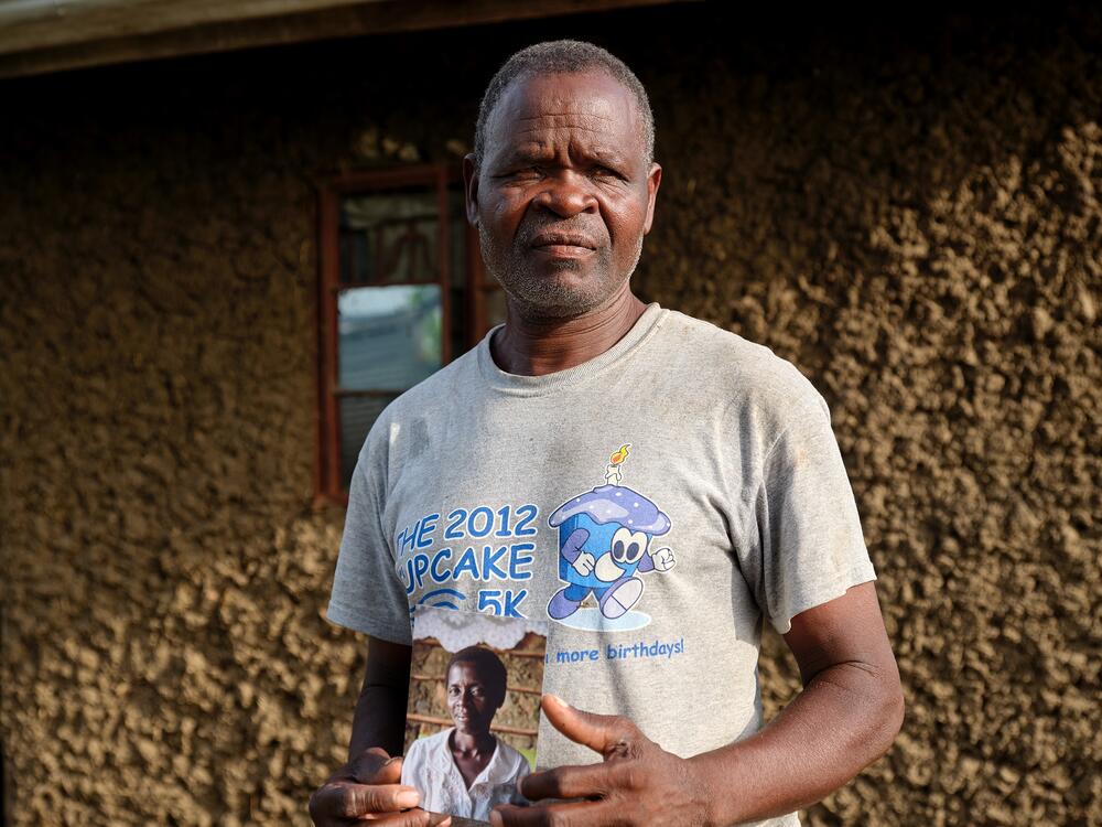 Jack Len'go holds a photo of his wife, Rose Atieno Abongo, who was a member of the No Sex for Fish group. The photo was taken in 2019, when an NPR team first reported on this story. Rose died in October 2024 of complications from HIV/AIDS. Len'go says she'd stopped taking her preventive drugs because she was not getting proper nutrition and the pills were making her sick. Rose is buried next to their home.