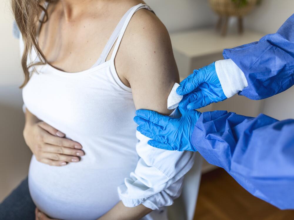 Female doctor giving the coronavirus vaccine to a young pregnant woman. Antibodies, immunize population. side effects, risk people, antibodies, new normal, covid-19.