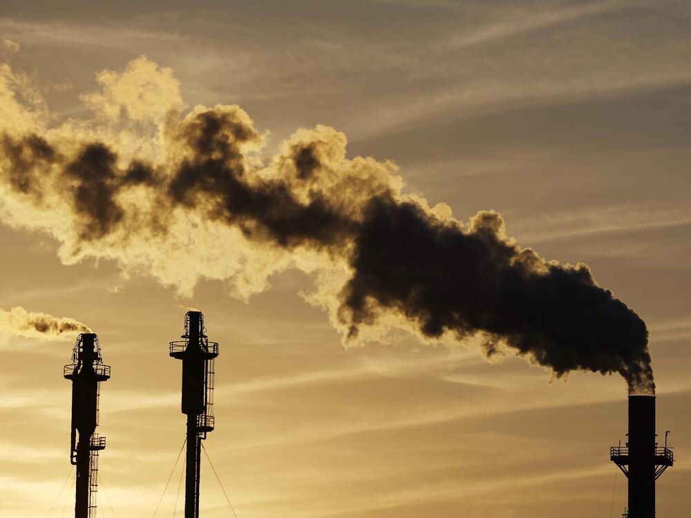 The sun begins to set beyond an oil refinery in California.