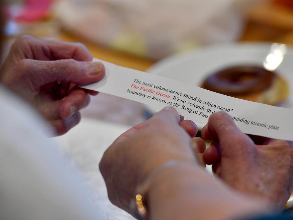 Guests at the Gathering Place Memory meet up help eachother to read a trivia question.