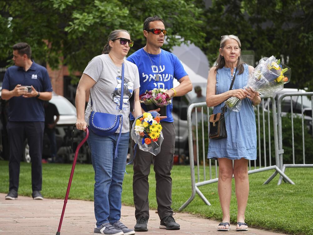 From left, Carrie Spyva-McIlvaine, Gabriel Velasco and Lisa Turnquist arrive to place bouquets of flowers at a memorial after Sunday's attack in Boulder, Colorado.