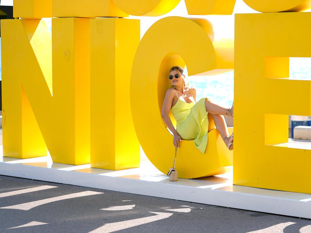 A woman poses for a photo on a sign spelling out the name of Nice, France, last summer. The city's name derives from Nike, the Greek goddess who heralds victory — not the word 