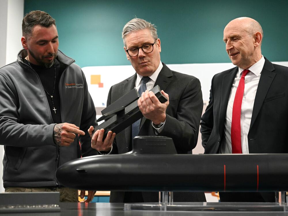 British Prime Minister Keir Starmer (center) and Britain's Defence Secretary John Healey (right) meet with BAE system apprentices as they look at a submarine model during a joint visit on March 20 in Barrow-in-Furness, United Kingdom. Starmer says the U.K. must upgrade its military in response to threats from Russia.