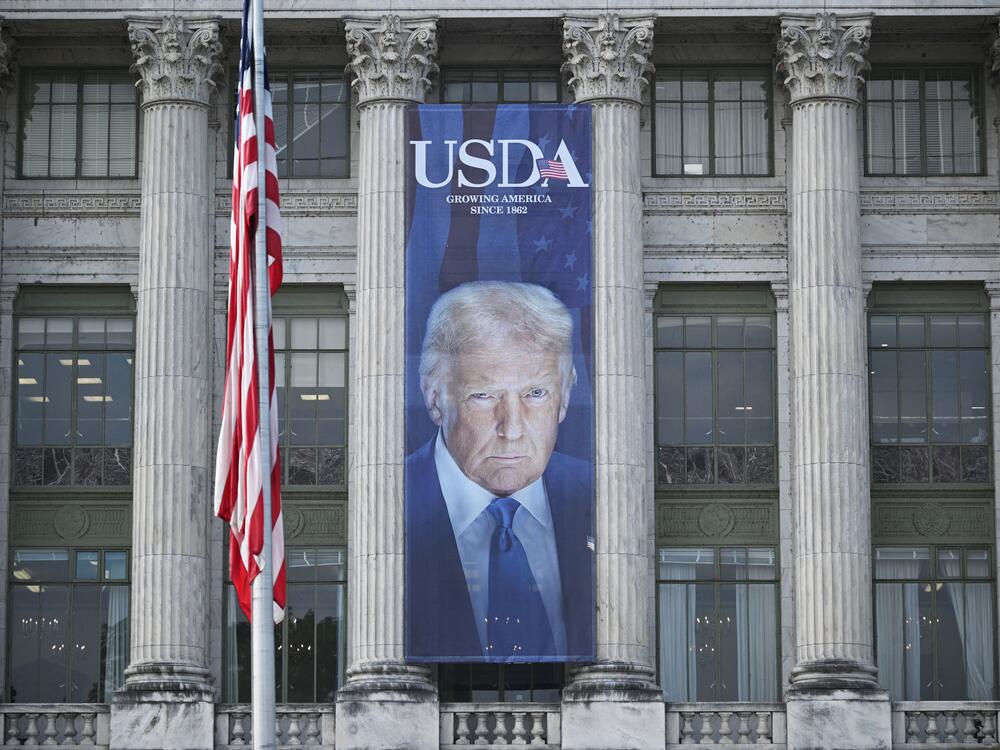 A banner showing an image of US President Donald Trump hangs on the side of a US Department of Agriculture building in Washington, DC, on May 16, 2025. USDA has put on hold a demand that states turn over sensitive data about food assistance recipients.