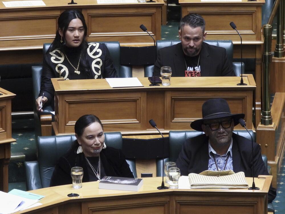 New Zealand lawmakers Hana-Rāwhiti Maipi-Clarke, top left, Debbie Ngarewa-Packer, bottom left, and Rawiri Waititi, bottom right, watch as other legislators debate their proposed bans in parliament in Wellington on Thursday, June 5, 2025.